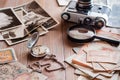 A watch on a chain, aged ruble bills, a film camera and black and white photographs on a wooden table. Vintage collection and