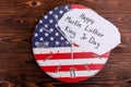 Clock in the coloring of the American flag on a wooden background with a big note