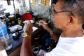 Watch repair man in his makeshift repair shop fixes an old wristwatch for a customer Royalty Free Stock Photo