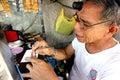 Watch repair man in his makeshift repair shop fixes an old wristwatch for a customer Royalty Free Stock Photo