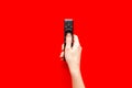 Watch TV concept. TV remote in hand on red background top-down copy space Royalty Free Stock Photo