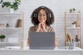 Watch video, lesson or webinar remotely at home. Happy african american woman in glasses and headphones looks at laptop