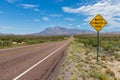 `Watch for water on Road` sign along a long straight road in the desert Royalty Free Stock Photo