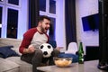 Watching a game. Cheerful young men drinking beer and eating snacks while watching TV Royalty Free Stock Photo