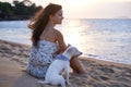 Watching the sunset at the beach. an attractive young woman enjoying the beach with her dog. Royalty Free Stock Photo