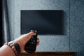 Watching Television Concept. Hand holding TV`s Remote to Control or Changing Channel. Relaxation in Modern Living Room. Focus on Royalty Free Stock Photo