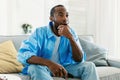 Watching TV at home. Emotional african american guy having rest, switching channels with remote controller, free space Royalty Free Stock Photo