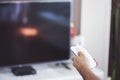 Watching TV. A man`s hand holding the TV remote control with a television in the background Royalty Free Stock Photo