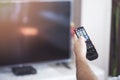 Watching TV. A man`s hand holding the TV remote control with a television in the background Royalty Free Stock Photo