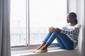 Watching the world go by. A beautiful young woman lost in thought while sitting on a window sill. Royalty Free Stock Photo