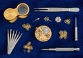 Watchmaking tools and components are arranged on a deep blue Royalty Free Stock Photo
