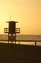 Watchtower on a beach and man walking his dog at sunset Royalty Free Stock Photo