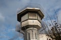 Watchtower of a correctional facility of a prison with a balustrade and two rows of barbed wire rolls in front of a dramatic sky Royalty Free Stock Photo