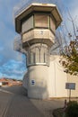 Watchtower of a correctional facility of a prison with a balustrade and two rows of barbed wire rolls in front of a dramatic sky. Royalty Free Stock Photo