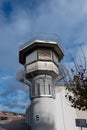 Watchtower of a correctional facility of a prison with a balustrade and two rows of barbed wire rolls in front of a dramatic sky Royalty Free Stock Photo