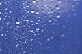 Some water droplets on a vibrant blue metallic surface. 