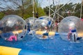 Water or Aquazorbing. Children play inside the inflatable transparent ball floating in swimming pool. Water walking or zorbing Royalty Free Stock Photo