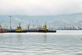 The water area of the sea cargo port with port tugboats in the foreground and a variety of gantry cranes in the background. Copy s