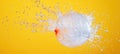 Water balloon exploding with splashing water droplets on yellow background