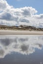 Water on the beach with mirror reflection of white clouds and dunes in the background Royalty Free Stock Photo