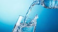 Water being poured from a bottle into a glass against a blue background Royalty Free Stock Photo