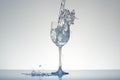 Water with blue tint pouring into a wineglass with splashes.