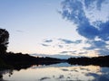 Water body with treeline with reflection against evening sky