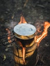 Water boiling in a metal pot on Swedish Fire Log. Burning a Swedish candle, swedish torch in summer Royalty Free Stock Photo