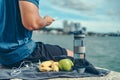 Water bottle, banana, earphone, green apple and towel on the ground beside young man rest after exercise and playing mobile phone Royalty Free Stock Photo