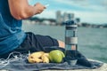 Water bottle, banana, earphone, green apple and towel on the ground beside young man rest after exercise and playing mobile phone Royalty Free Stock Photo