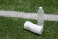 Water bottle sport drink and towel in football field on green artificial grass background, close up with copy space Royalty Free Stock Photo