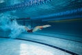 Water bubbles demonstrating speed. Young man, swimming athlete in motion in pool training, preparing for competition Royalty Free Stock Photo