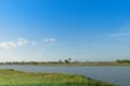 Water canal in field, trees and palm trees, blue sky background Royalty Free Stock Photo