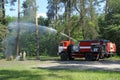 Water cannon of a fire engine shooting a high-velocity stream of water, firemen fighting fire in forest