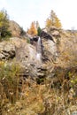 Water cascading over rocks, waterfall and autumn colors in the mountains, yellow and red trees Royalty Free Stock Photo