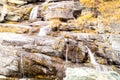 Water cascading over rocks, waterfall and autumn colors in the mountains, yellow and red trees Royalty Free Stock Photo