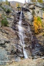 Water cascading over rocks, waterfall and autumn colors in the mountains, yellow and red trees Royalty Free Stock Photo