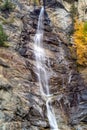 Water cascading over rocks, waterfall and autumn colors in the mountains, yellow and red trees Royalty Free Stock Photo