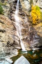 Water cascading over rocks, waterfall and autumn colors in the mountains, yellow and red trees Royalty Free Stock Photo