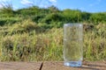 Water. Cold mineral water in a glass beaker. Drops of drinking water on the glass and raindrops on the grass Royalty Free Stock Photo