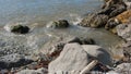 Water comes to rocky shore. Concept. Dirty water on rocky shore. Dirty sea water with small waves breaks on rocks. Rocky