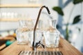 Water crane on the background of many glass large vases standing on a wooden countertop