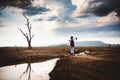 Hopeless and lonely farmer sit on cracked earth near drying water Royalty Free Stock Photo