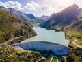 Water dam and reservoir lake in Swiss Alps generating hydroelectricity. Aerial view of arch dam between mountains. Hydropower