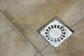 Water drain vent in kitchen, bathroom or basement ceramic tiled old vintage floor. Geometric abstract beige background