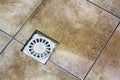 Water drain vent in kitchen, bathroom or basement ceramic tiled old vintage floor. Geometric abstract beige background
