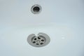 Water is draining in drain hole of the sink in bathroom, closeup view. Royalty Free Stock Photo