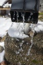 Water dripping from downspout after the snow melts in spring