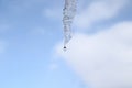 Water dripping from an icicle against a blue sky with clouds Royalty Free Stock Photo