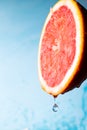 Water drips from half a grapefruit. Splashes and drops fly from a piece of grapefruit symbolizing the brightness and freshness of Royalty Free Stock Photo